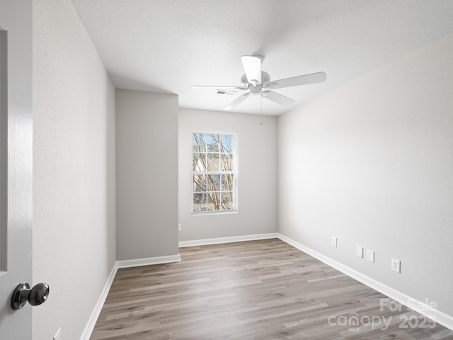 spare room with visible vents, ceiling fan, a textured ceiling, light wood-type flooring, and baseboards