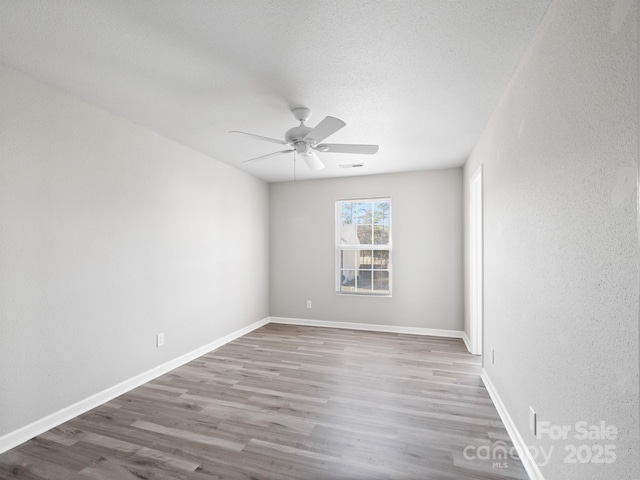 unfurnished room with baseboards, visible vents, a ceiling fan, wood finished floors, and a textured ceiling