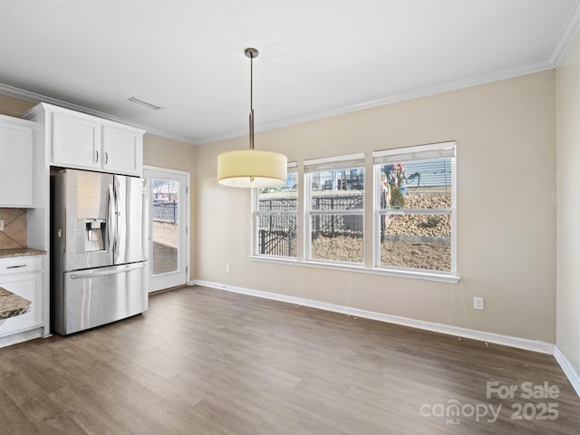 kitchen featuring stainless steel refrigerator with ice dispenser, white cabinetry, crown molding, hanging light fixtures, and decorative backsplash