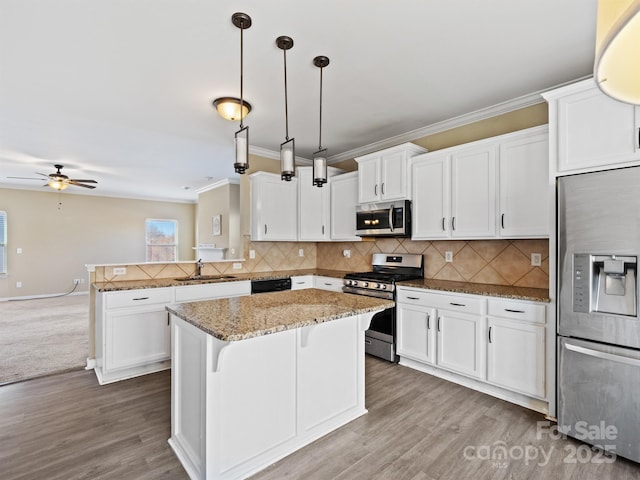 kitchen featuring appliances with stainless steel finishes, sink, a breakfast bar area, hanging light fixtures, and a center island