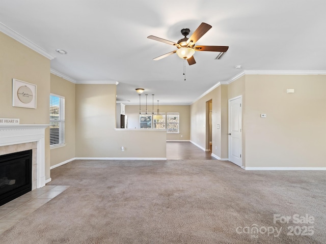 unfurnished living room featuring a tile fireplace, light colored carpet, ceiling fan, and crown molding