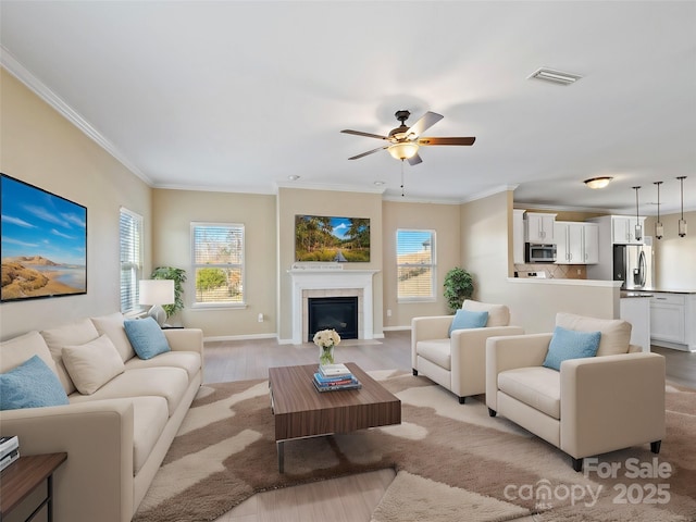 living room featuring ornamental molding, ceiling fan, and light wood-type flooring