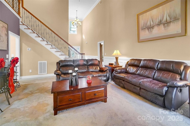 carpeted living room with a towering ceiling, stairs, visible vents, and a chandelier