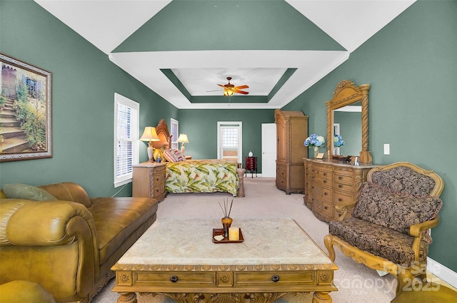 carpeted bedroom with baseboards, a raised ceiling, and a ceiling fan