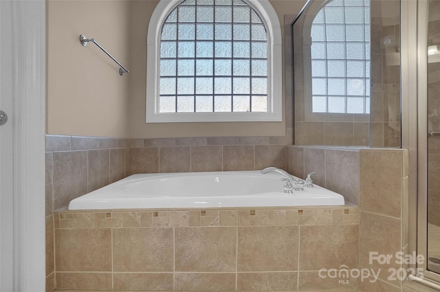 full bathroom with a garden tub, plenty of natural light, and tiled shower