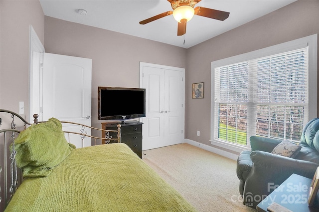 bedroom with a ceiling fan, a closet, carpet flooring, and baseboards