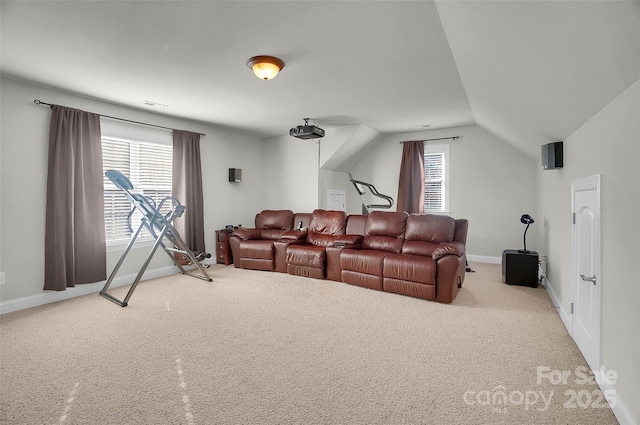 carpeted home theater room featuring lofted ceiling, visible vents, and baseboards