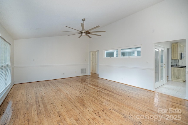 unfurnished living room with light wood-type flooring, high vaulted ceiling, and ceiling fan