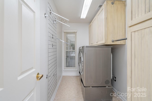 clothes washing area featuring cabinets and washer and dryer