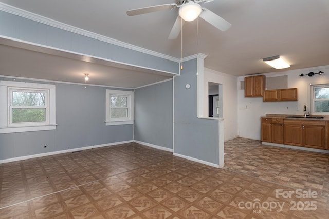 unfurnished living room with ceiling fan, ornamental molding, and sink