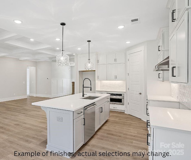 kitchen featuring sink, white cabinetry, stainless steel appliances, hanging light fixtures, and an island with sink