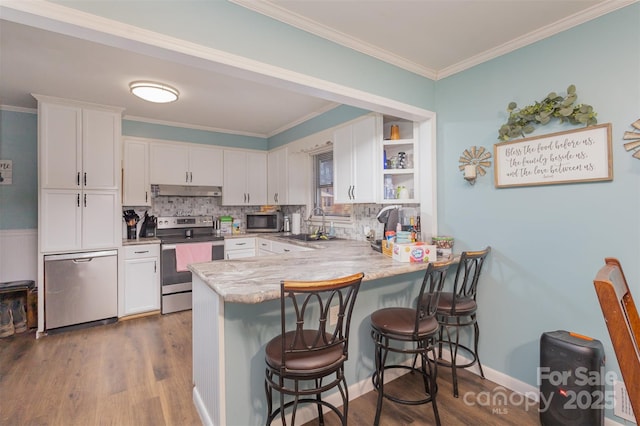 kitchen featuring white cabinets, a kitchen breakfast bar, appliances with stainless steel finishes, dark hardwood / wood-style flooring, and kitchen peninsula