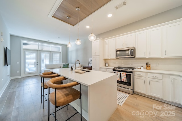 kitchen featuring white cabinetry, sink, a center island with sink, and appliances with stainless steel finishes