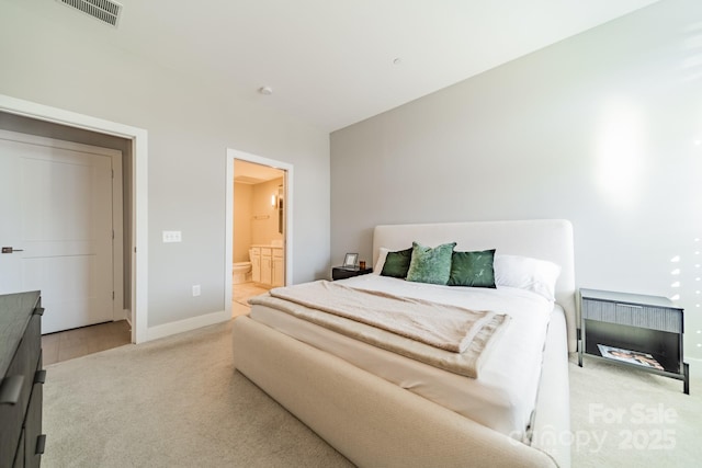 bedroom featuring ensuite bathroom and light carpet