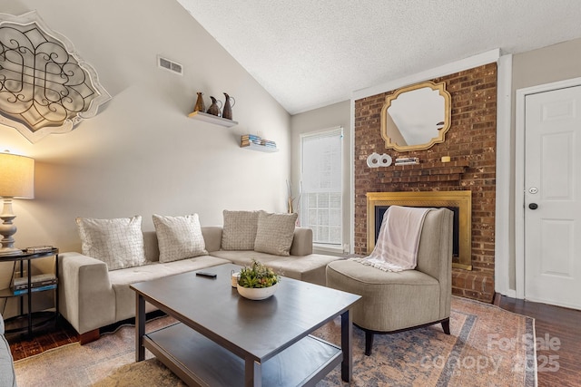 living room featuring a fireplace, a textured ceiling, hardwood / wood-style flooring, and lofted ceiling