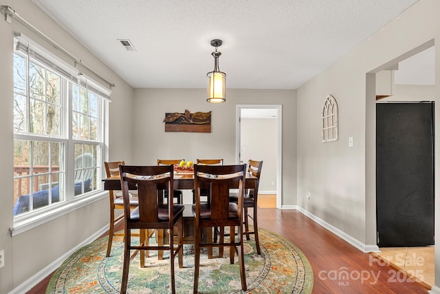 dining space featuring wood-type flooring and a textured ceiling