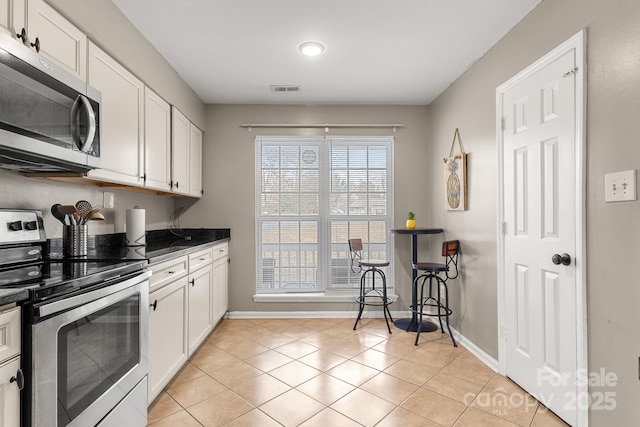 kitchen with white cabinets, light tile patterned floors, and appliances with stainless steel finishes