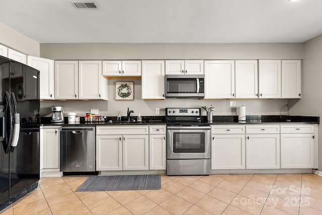 kitchen with white cabinetry, sink, stainless steel appliances, dark stone counters, and light tile patterned floors