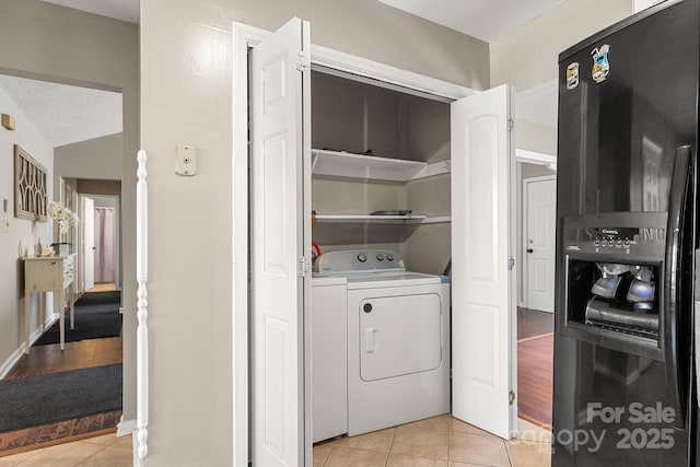 laundry area with independent washer and dryer, light tile patterned floors, and a textured ceiling