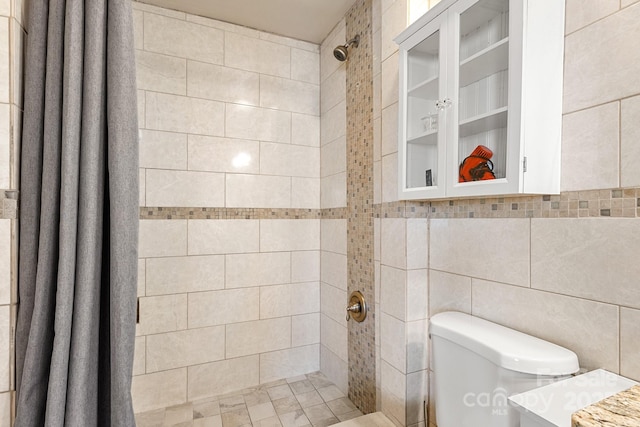 bathroom featuring walk in shower, vanity, toilet, and tile walls