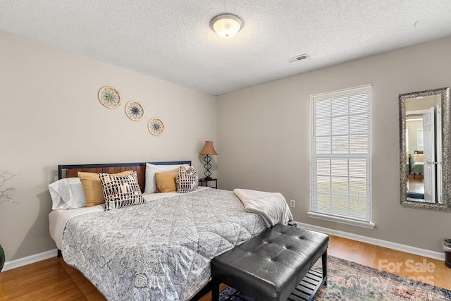 bedroom with hardwood / wood-style floors and a textured ceiling