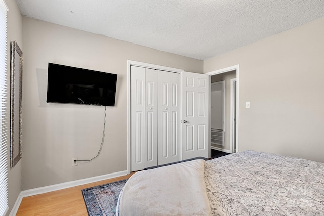 bedroom featuring wood-type flooring, a textured ceiling, and a closet