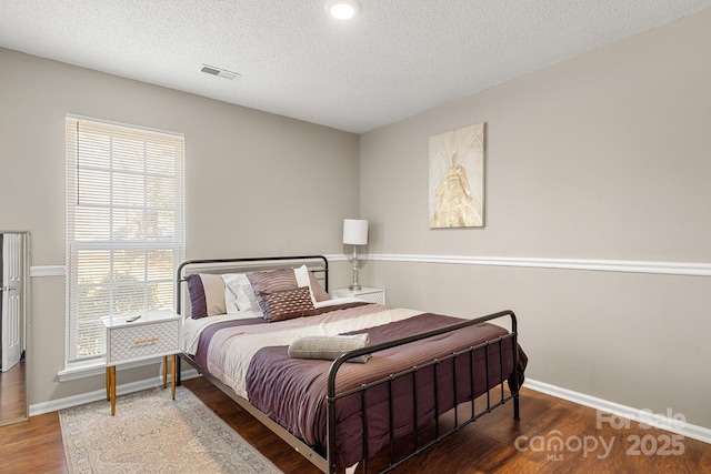 bedroom featuring dark hardwood / wood-style flooring and a textured ceiling