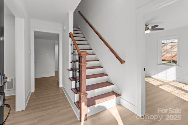 stairs featuring hardwood / wood-style flooring and ceiling fan