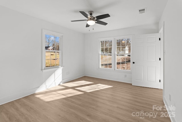 empty room featuring plenty of natural light, ceiling fan, and light hardwood / wood-style floors