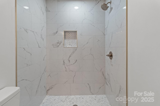 bathroom featuring a tile shower and toilet