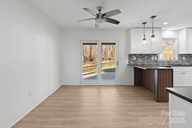 kitchen featuring a wealth of natural light, white cabinetry, light hardwood / wood-style flooring, and pendant lighting