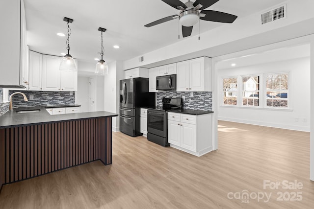 kitchen featuring black appliances, white cabinets, sink, hanging light fixtures, and light hardwood / wood-style flooring