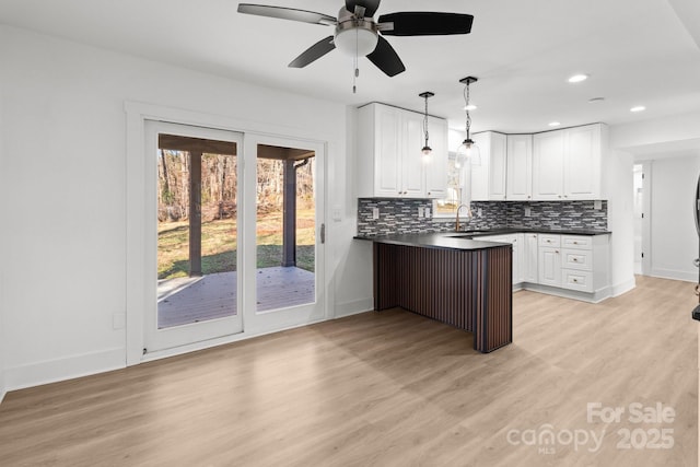 kitchen with sink, hanging light fixtures, light hardwood / wood-style flooring, ceiling fan, and white cabinetry