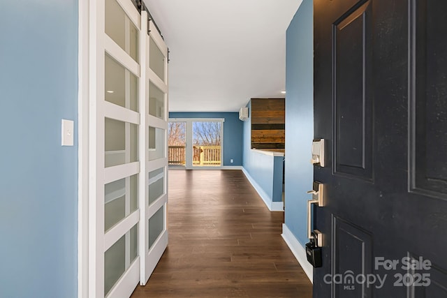 hallway featuring a barn door and dark wood-type flooring