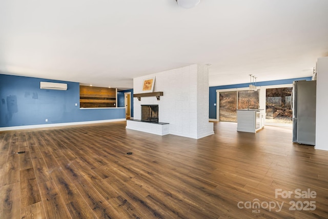 unfurnished living room with an AC wall unit, a fireplace, and hardwood / wood-style floors