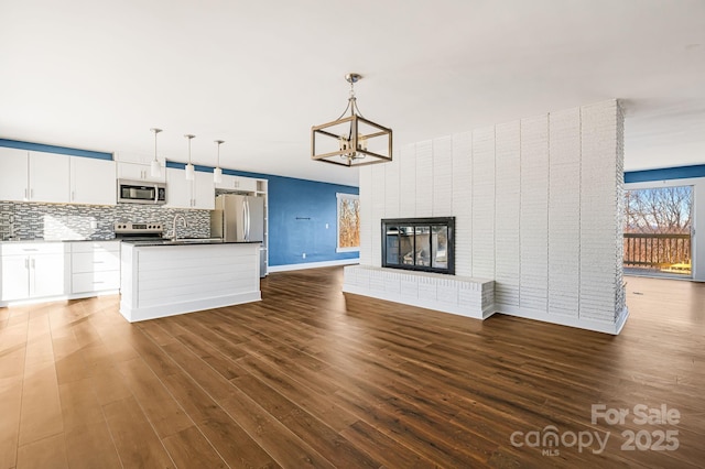 unfurnished living room featuring a fireplace, dark hardwood / wood-style flooring, and a chandelier