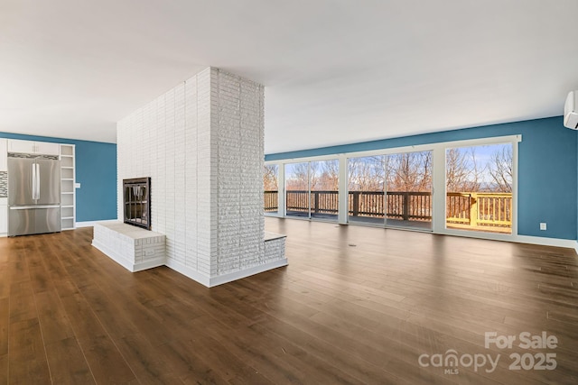 unfurnished living room featuring a wall mounted air conditioner, dark hardwood / wood-style flooring, and a fireplace