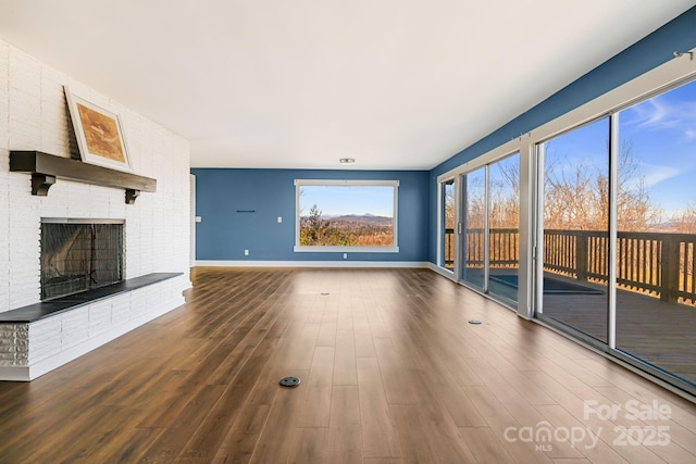 unfurnished living room featuring wood-type flooring and a brick fireplace