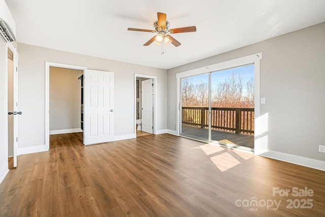 unfurnished bedroom featuring ceiling fan, wood-type flooring, a spacious closet, and access to outside