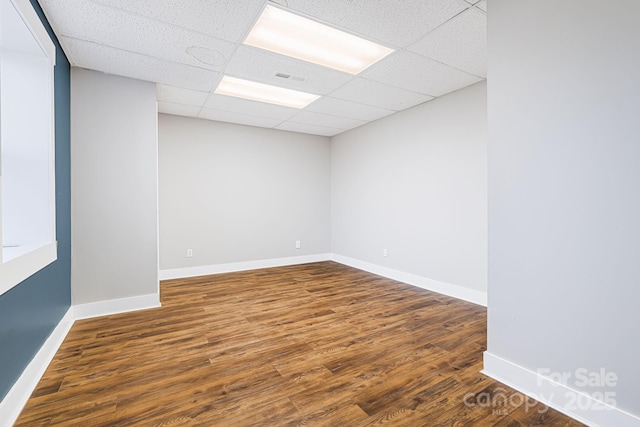 empty room featuring dark hardwood / wood-style flooring and a paneled ceiling