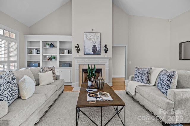 living room with hardwood / wood-style floors, vaulted ceiling, and a tiled fireplace