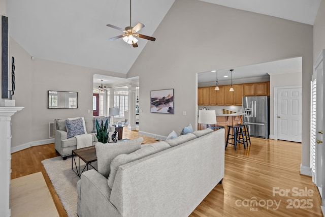 living room featuring ceiling fan with notable chandelier, light hardwood / wood-style floors, and high vaulted ceiling