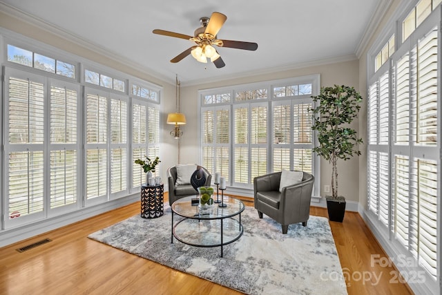 sitting room with ceiling fan, light wood-type flooring, and crown molding