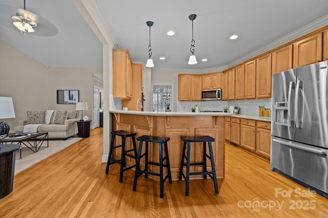 kitchen with kitchen peninsula, appliances with stainless steel finishes, light wood-type flooring, tasteful backsplash, and a breakfast bar area