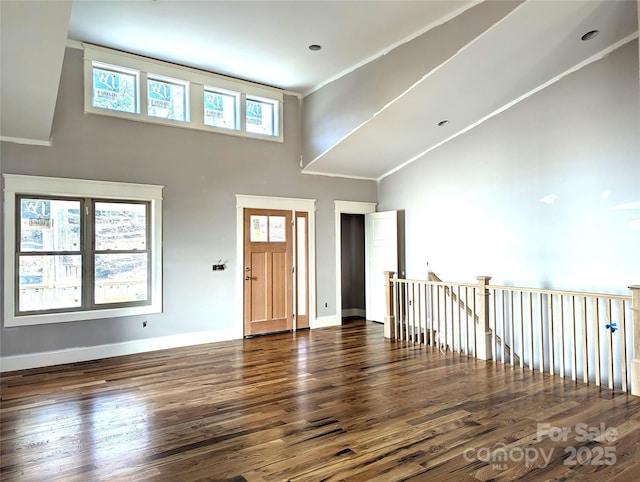 entryway featuring wood finished floors, baseboards, and high vaulted ceiling