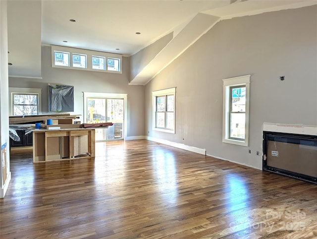 unfurnished living room with dark wood-type flooring and a high ceiling