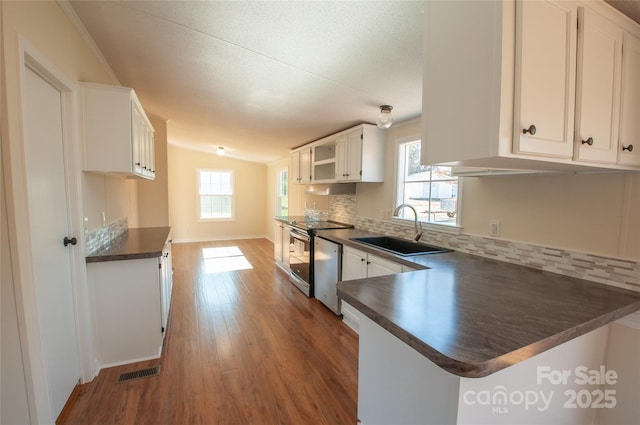 kitchen with white cabinetry, sink, kitchen peninsula, lofted ceiling, and appliances with stainless steel finishes