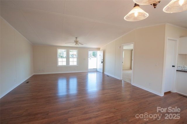 empty room with dark hardwood / wood-style floors, vaulted ceiling, ceiling fan, and ornamental molding