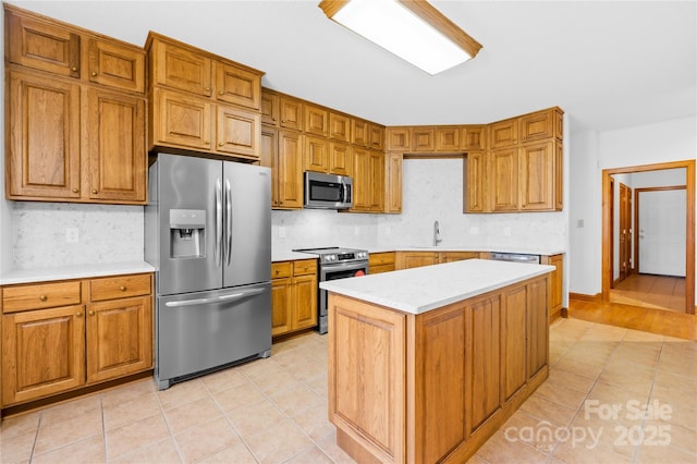 kitchen with appliances with stainless steel finishes, tasteful backsplash, light tile patterned floors, a kitchen island, and sink