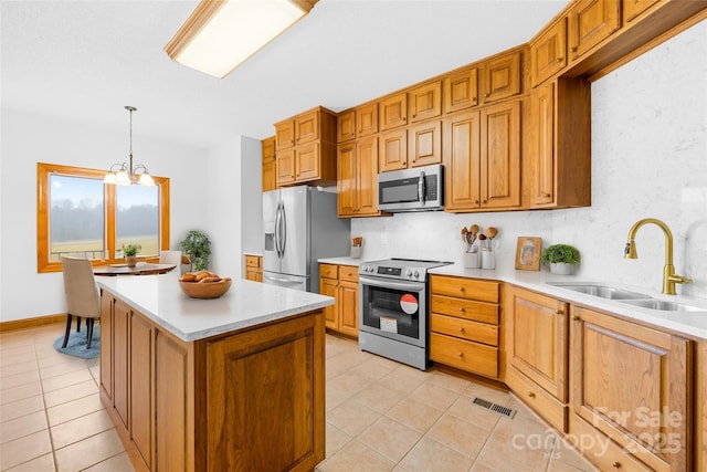 kitchen with appliances with stainless steel finishes, sink, a chandelier, light tile patterned floors, and hanging light fixtures